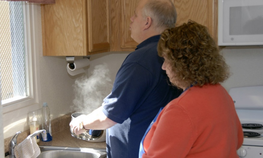 A couple cooks together in their kitchen.